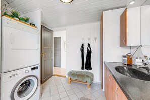 Eine kleine Küche mit Waschmaschine, einer Holzbank und einem Spülbecken.