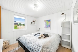 Ein Schlafzimmer mit Bett, Fenster, Regal und Schreibtisch.