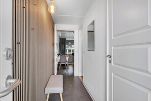 A hallway with a bench, a door, and a dining area in the background. - Modernized holiday apartment centrally located in Søndervig with 200 meters to. (Ringkøbing)
