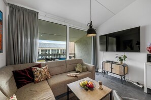 Ein modernes Wohnzimmer mit einer Couch, einem Couchtisch mit Obst, einem Schrank und einem großen Fenster.