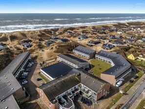An aerial view of a coastal area with buildings, a parking lot, and a beach. - Modernized holiday apartment centrally located in Søndervig with 200 meters to. (Ringkøbing)