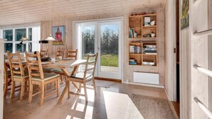 Una stanza con rivestimento in legno, un tavolo da pranzo, sedie, librerie e un'ampia finestra.