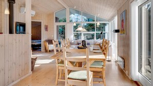 Un interno in legno con zona pranzo, ampie finestre e televisore.