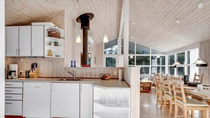 Una cucina moderna con mobili bianchi, un'isola centrale e una zona pranzo con sedie in legno.