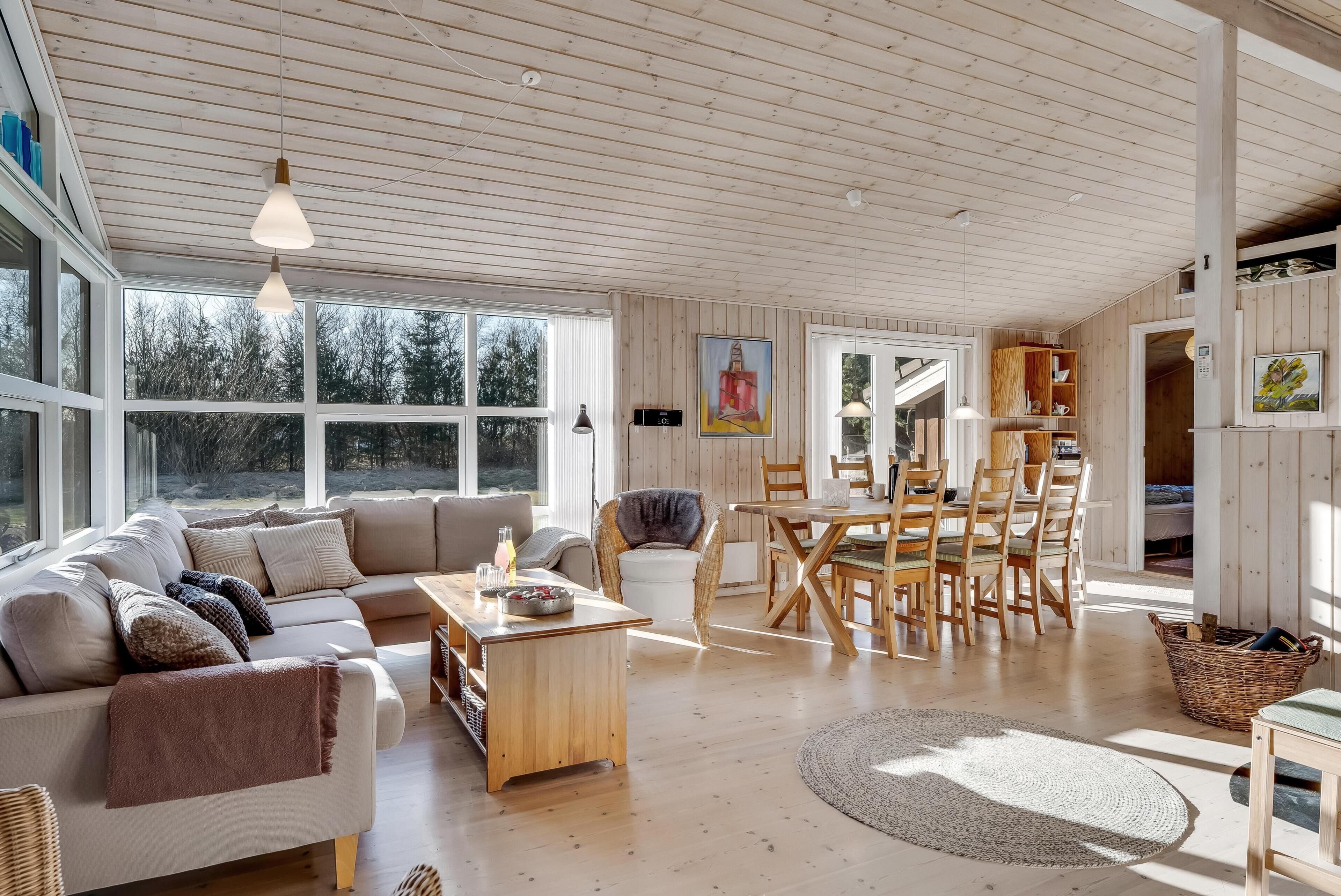 Een ruime woonkamer met een bank, eettafel, stoelen en een groot raam.