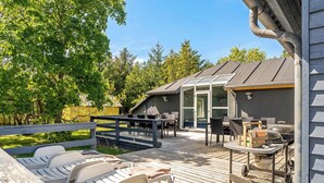 A deck with lounge chairs, a grill, and a covered patio area. - Lovely 16-person pool house with spa, sauna and large terrace (Vestervig)
