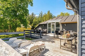 A deck with lounge chairs, a grill, and a covered patio area. - Lovely 16-person pool house with spa, sauna and large terrace (Vestervig)