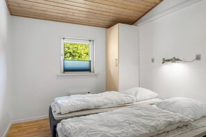 A bedroom with a window, a bed, and a wall-mounted light fixture. - Lovely 16-person pool house with spa, sauna and large terrace (Vestervig)