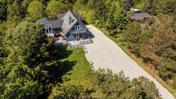 A large house with a gravel driveway, surrounded by dense forest. - Lovely 16-person pool house with spa, sauna and large terrace (Vestervig)