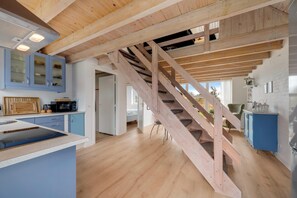 Eine moderne Küche mit einer Holztreppe, einem blauen Schrank und einer Mikrowelle.