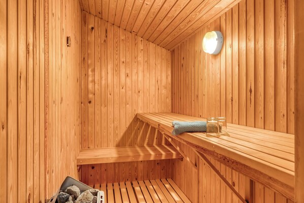 Eine Holzsauna mit Bänken, einer Lampe und einem Handtuch auf einer der Bänke.