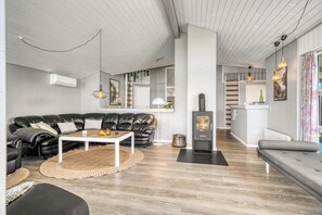 Ein modernes Wohnzimmer mit Ledersofa, Couchtisch, Kamin und einer Küchenzeile im Hintergrund.