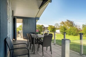 Eine Terrass mit Tisch, Stühlen, einem Blumentopf und Blick auf die Nachbarschaft.