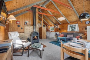 Ein gemütliches Blockhaus mit Kamin, Holzwänden, einem Essbereich und einer Küche.