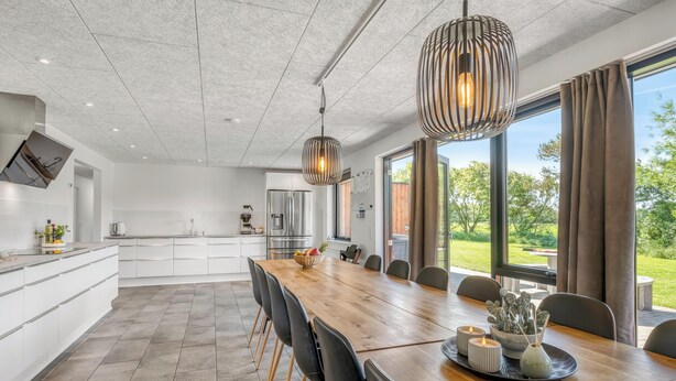 Eine moderne Küche mit weißen Schränken, einer großen Kochinsel und einem Essbereich mit Holztisch und Stühlen.