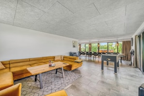 A modern lounge area with a sofa, table, and foosball table. - Large, completely renovated activity house with wilderness bath and outdoor. (Ulfborg)