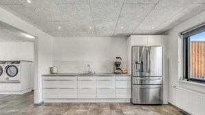 Eine moderne Küche mit einem Edelstahl-Kühlschrank, einer integrierten Waschmaschine und einem großen Fenster.