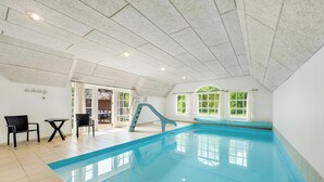Una piscina interior con tobogán, una pequeña mesa y dos sillas.