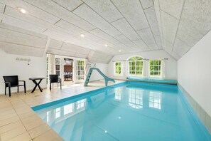 Ein Hallenbad mit Rutsche, einem kleinen Tisch und zwei Stühlen.