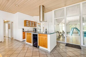 Eine moderne Küche mit Holzschränken, einer Edelstahl-Dunstabzugshaube und einer großen Kochinsel.