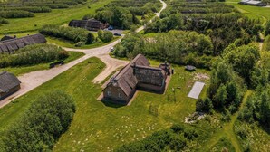 Vista aérea de una zona rural con casas de techo de paja, un camino serpenteante y campos abiertos.