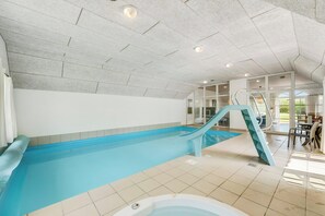 Ein Hallenbad mit Rutsche, Whirlpool und Blick ins Freie.