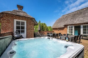 Ein Whirlpool in einem Hinterhof mit einem Ziegelhaus und strohgedeckten Gebäuden.