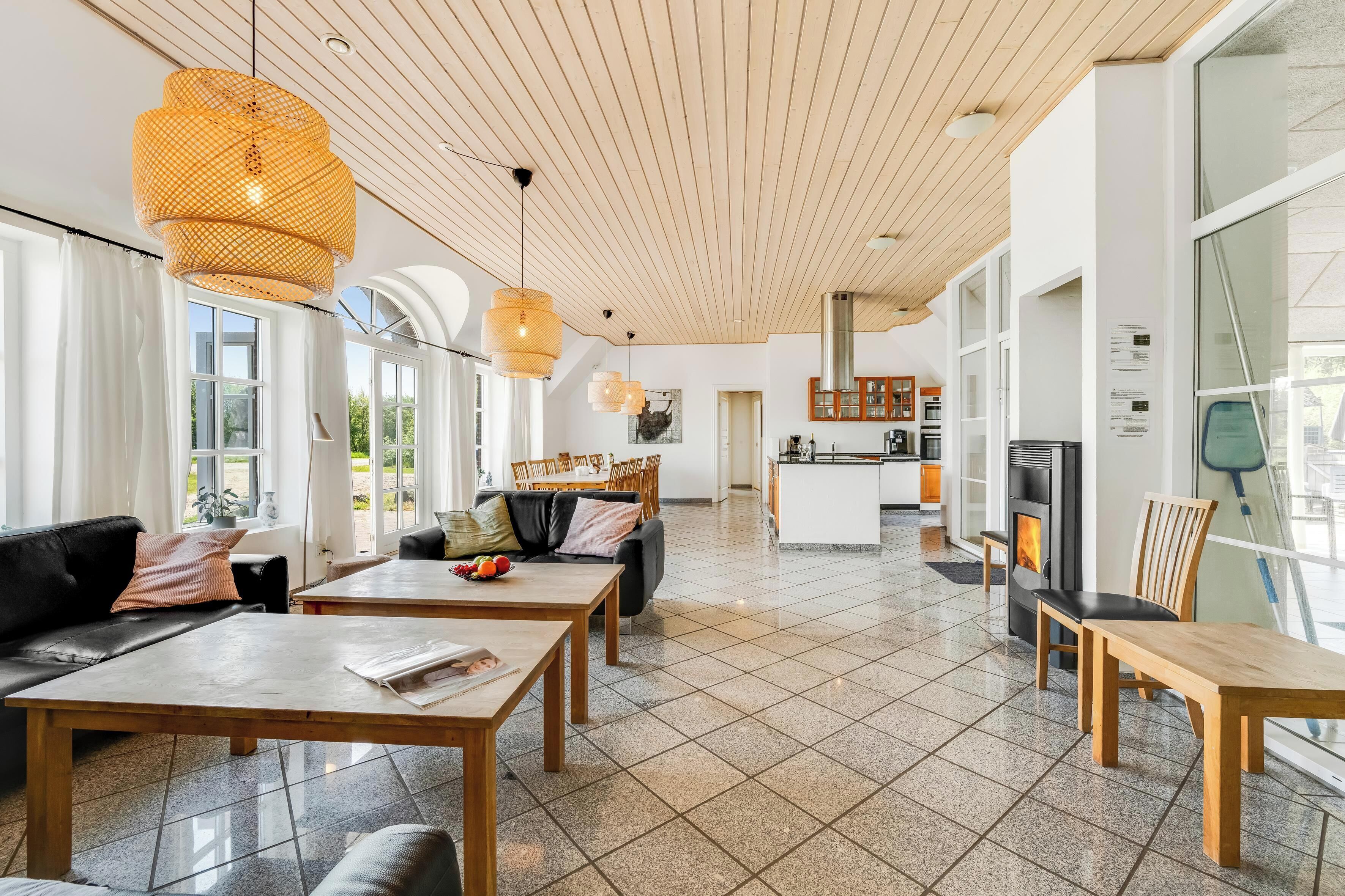 A spacious living area with a fireplace, wooden furniture, and large windows.