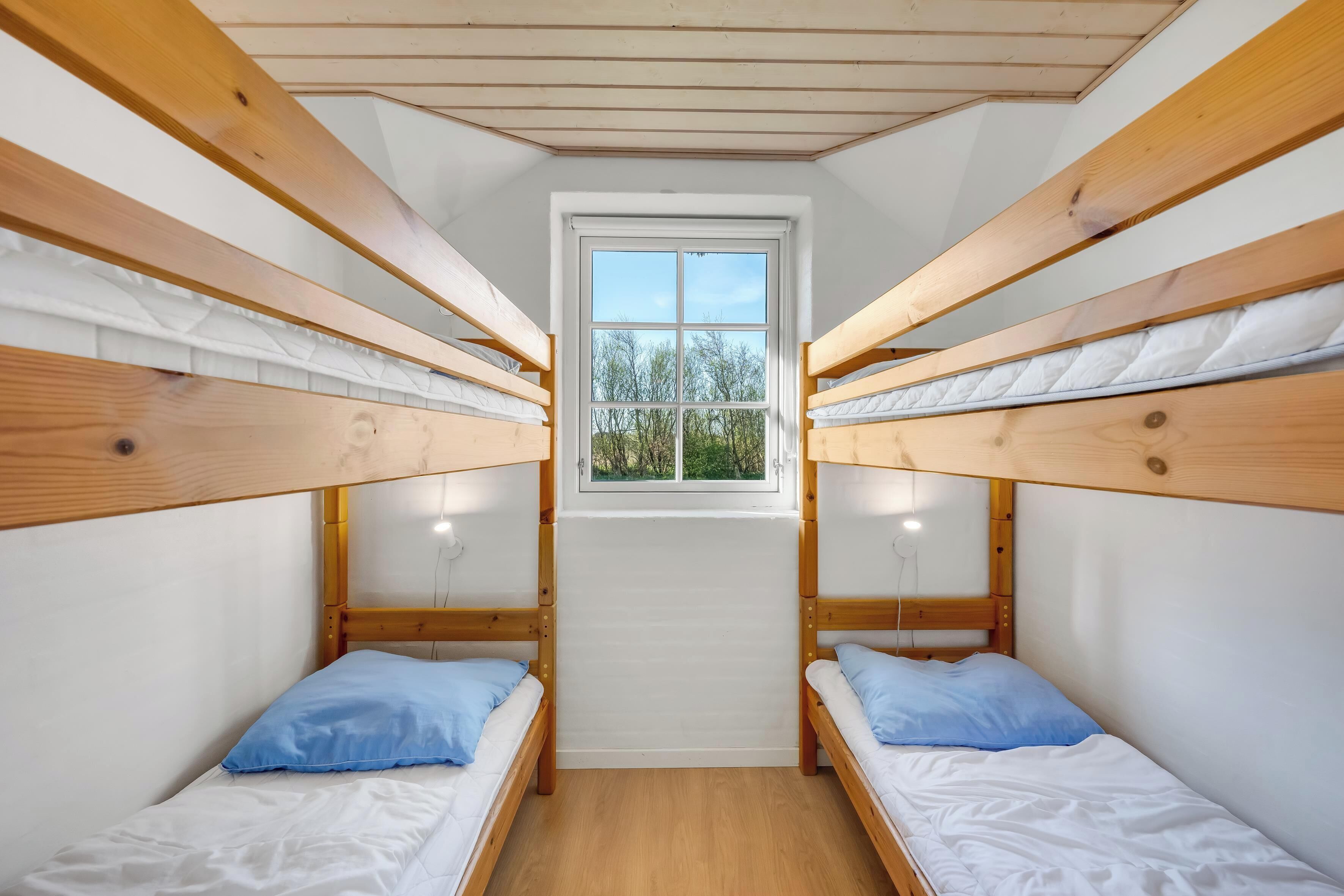 Une chambre de dortoir avec des lits superposés, une fenêtre et une vue sur les arbres.