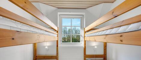 Une chambre de dortoir avec des lits superposés, une fenêtre et une vue sur les arbres.