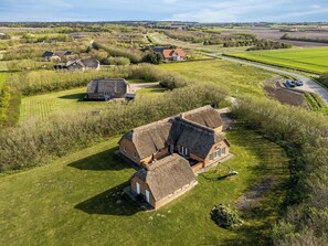 A rural landscape with traditional thatched-roof houses, a winding road, and expansive fields. - Large holiday home with pool, hot tub and activity room in Husby (Ulfborg)