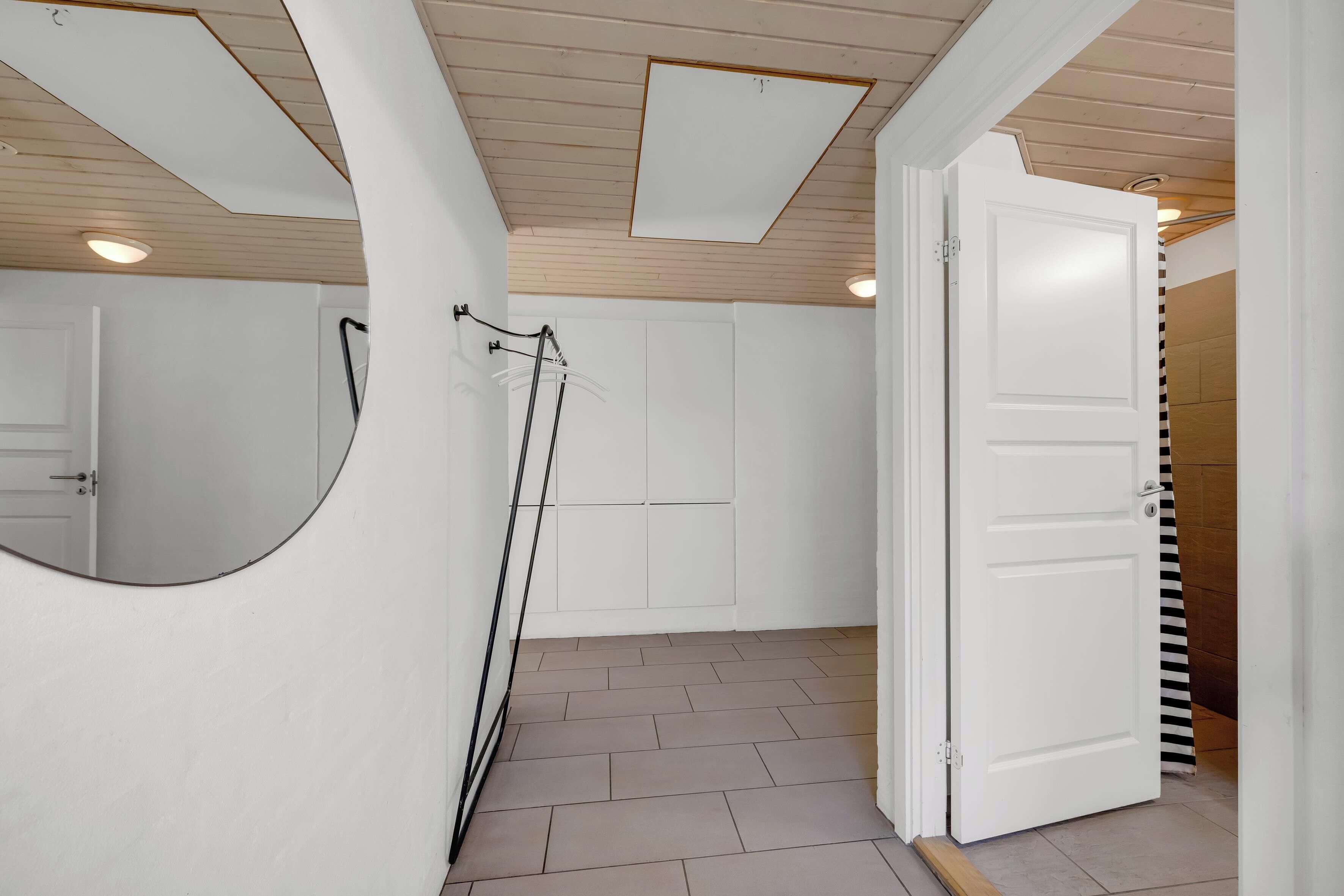 A room with a white door, a mirror, and a shower area.