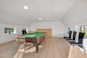 Ein Billardtisch in einem Raum mit Fliesenboden, weißer Decke und einem Fenster.
