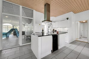 Eine moderne Küche mit einer zentralen Kochinsel, weißen Schränken und einer Holzbalkendecke.