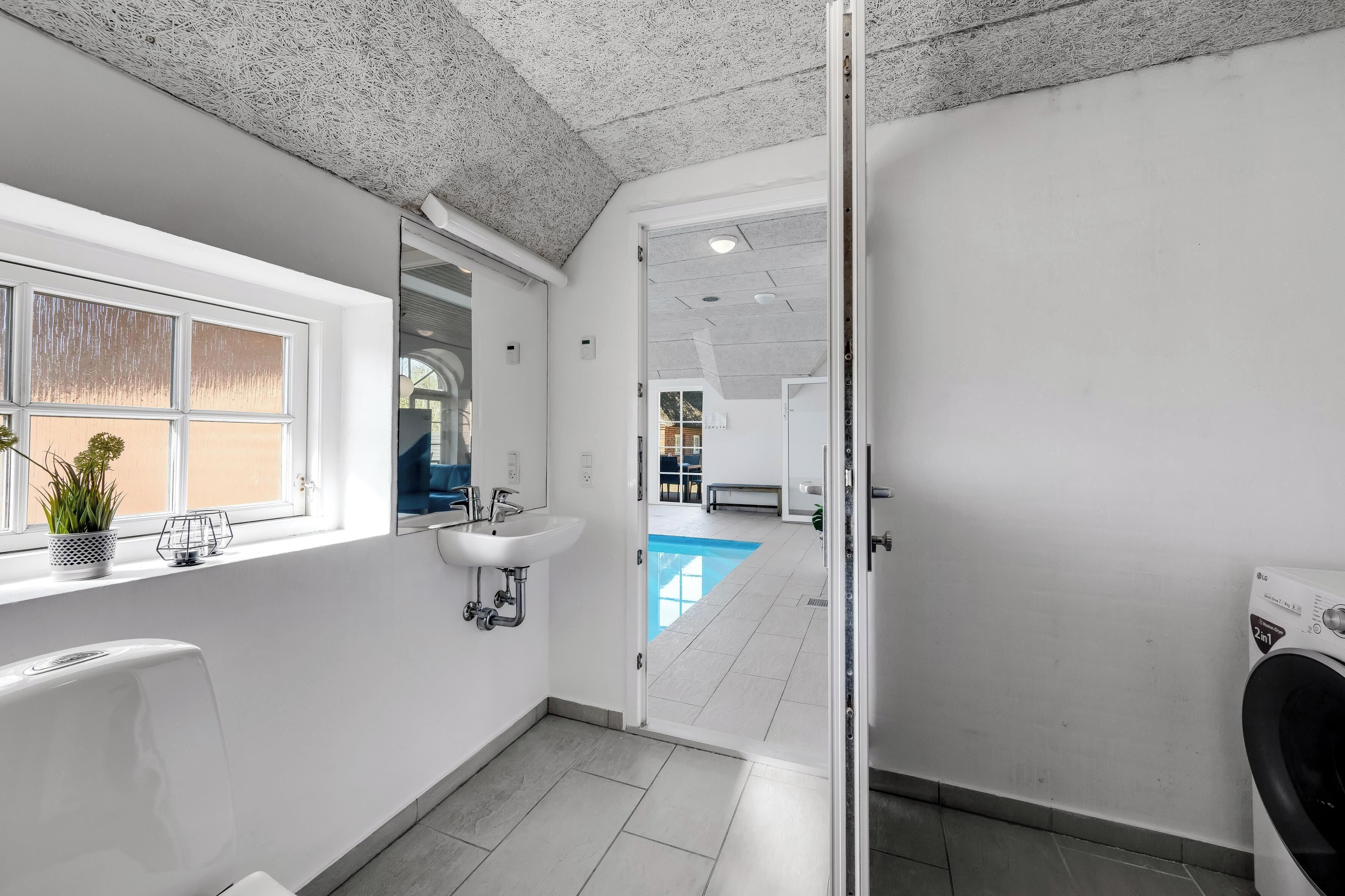 A modern bathroom with a large window, a sink, a toilet, and a shower area.