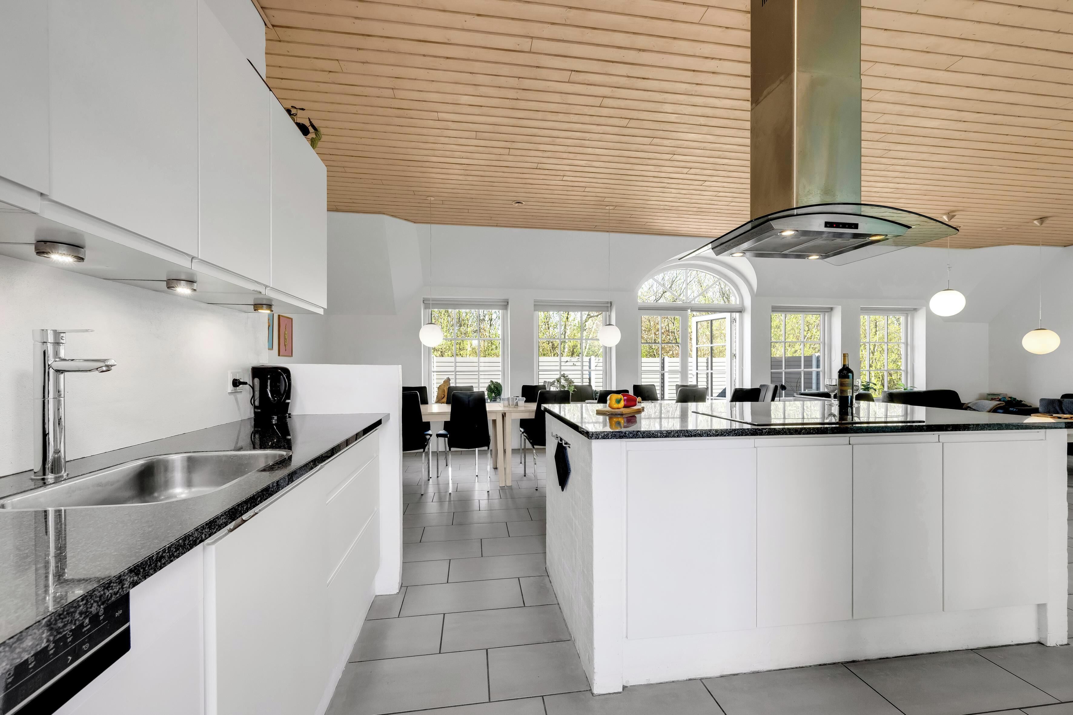 Een moderne keuken met witte kastjes, een centraal eiland en een eetgedeelte met natuurlijk licht.