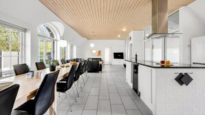 Uma cozinha moderna com uma ilha central, armários brancos e teto de madeira.