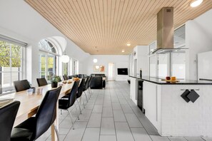 A modern kitchen with a central island, white cabinetry, and a wooden ceiling. - 18-person pool house with hot tub, infrared sauna and activity room. (Ulfborg)
