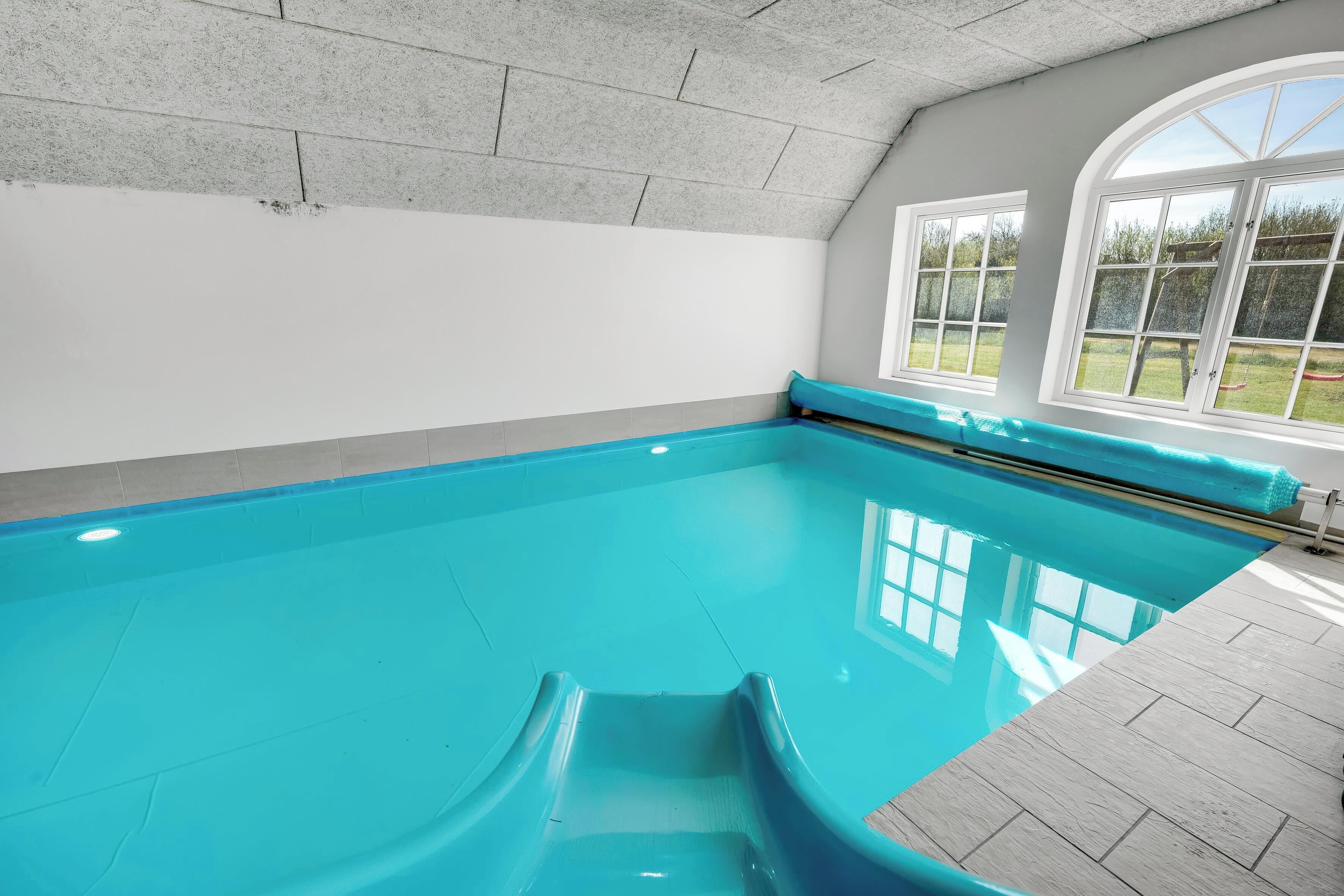 Une piscine intérieure offrant une vue dégagée sur l’extérieur grâce à de grandes fenêtres.