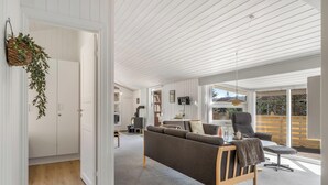 Een moderne woonkamer met een bank, een fauteuil en een eethoek.