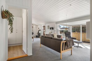 A modern living room with a sofa, a chair, and a dining area. - Holiday home with sauna and enclosed terrace in Vorupør. (Thisted)