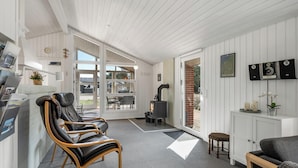 Een modern interieur met een open haard, zithoek en uitzicht door grote ramen.