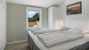 Een slaapkamer met een bed, een raam, een tv aan de muur en uitzicht op de omgeving.