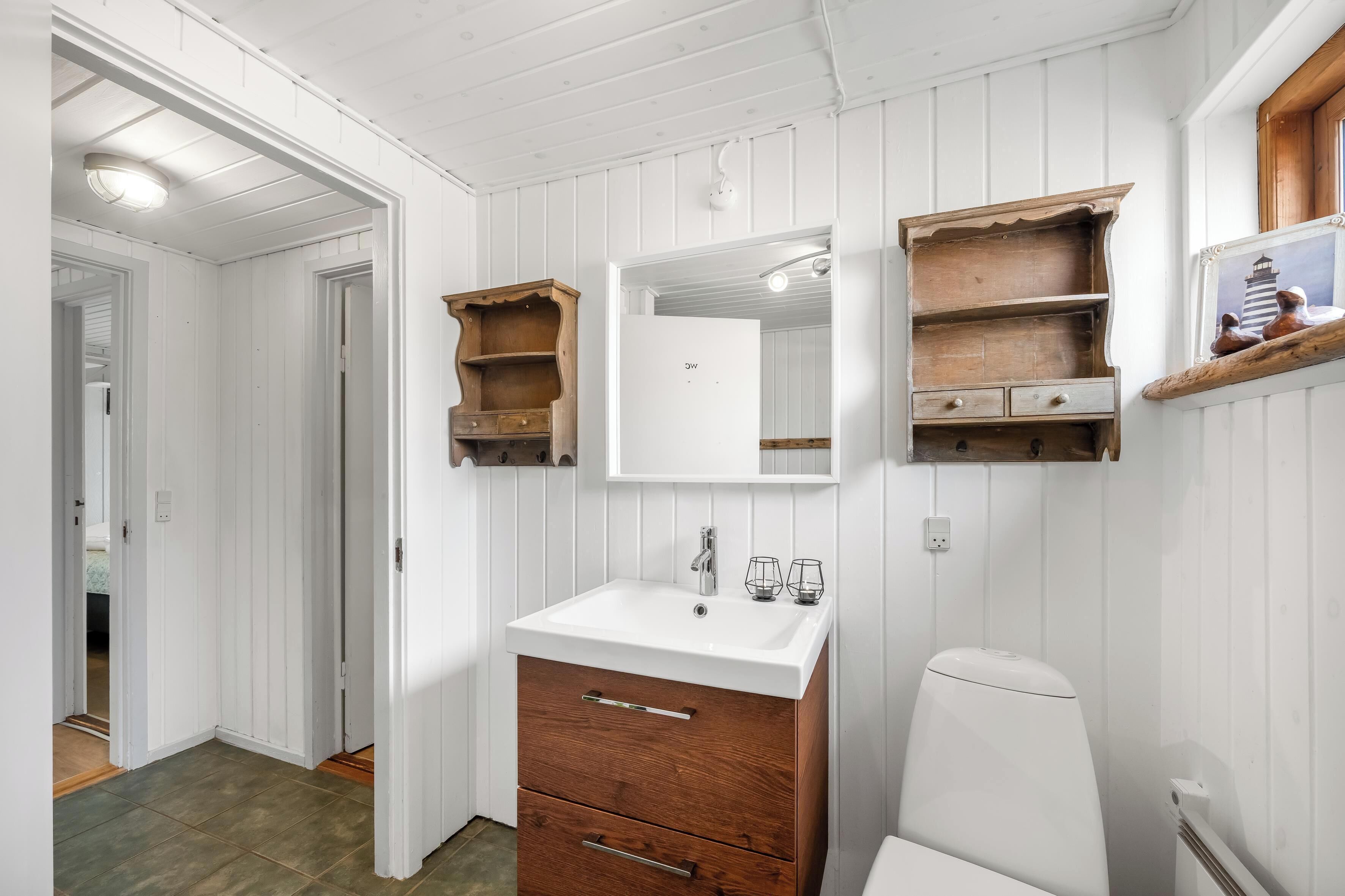 A bathroom with a white sink, wooden cabinets, and a mirror.