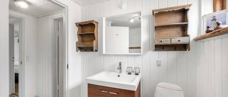 A bathroom with a white sink, wooden cabinets, and a mirror.