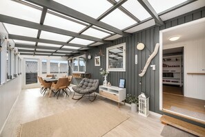 Ein geräumiges Zimmer mit Essbereich, einem Schaukelstuhl, einem weißen Konsolentisch und Blick durch ein Oberlicht.