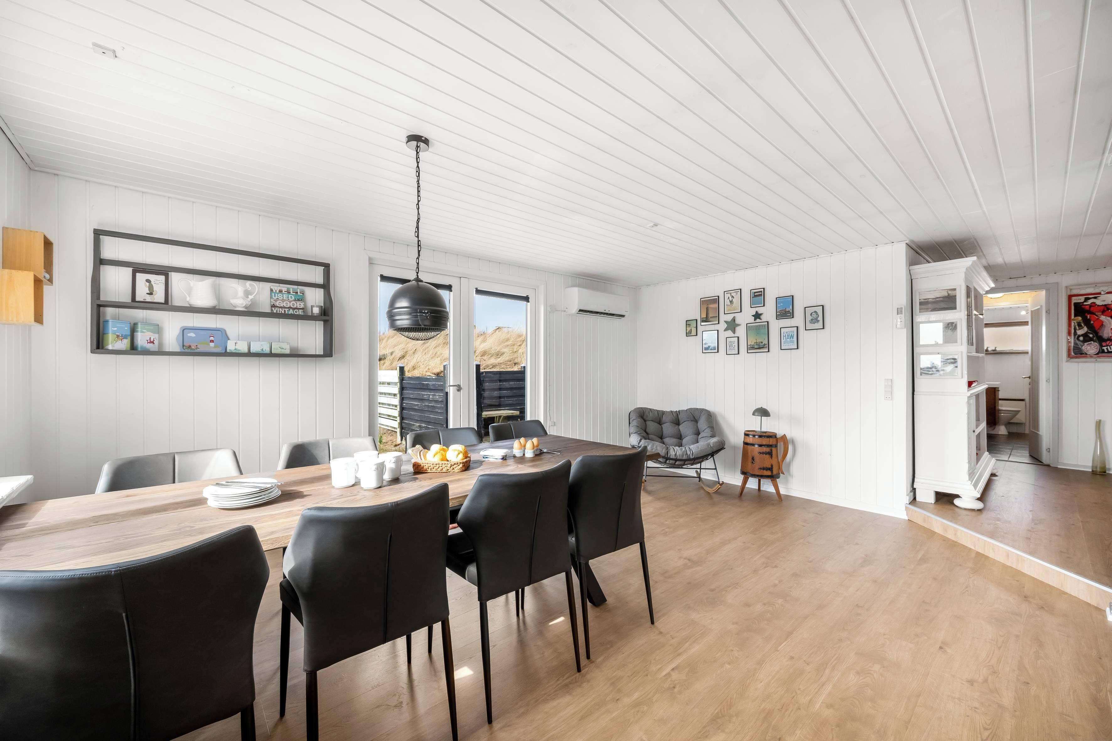 A dining area with a wooden table, black chairs, and a hanging light fixture.