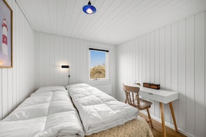 A bedroom with a bed, a desk, a chair, a window, and a wall-mounted light fixture. - Holiday home with enclosure for dogs, 500 meters from the North Sea (Ringkøbing)