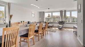 A modern kitchen with wooden chairs, a dining table, and large windows. - 14-person holiday home in Agger with wilderness bath and outdoor sauna (Vestervig)