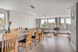 A modern kitchen with wooden chairs, a dining table, and large windows. - 14-person holiday home in Agger with wilderness bath and outdoor sauna (Vestervig)